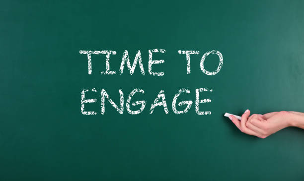 istock Woman pointing at chalkboard with text Time To Engage, closeup 1345536992