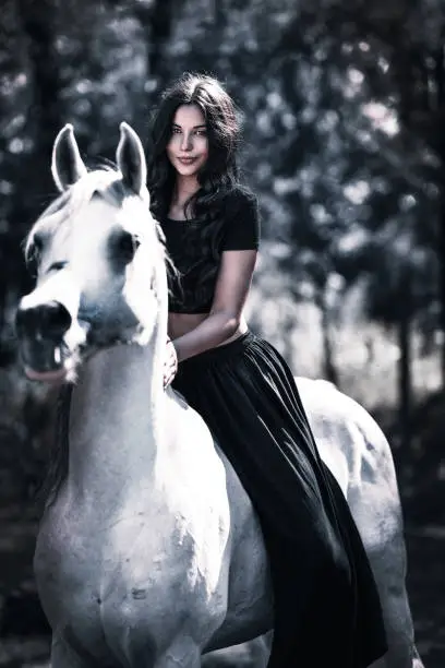 Photo of Cute Gypsy Female Riding Her White Horse On Ranch