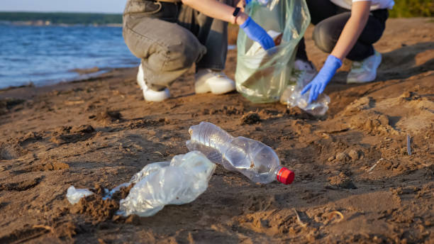 istock Two unrecognizable persons in gloves collect plastic trash on the river bank 1345539055