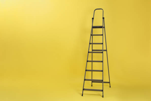 istock Metal stepladder on yellow background. Space for text 1345539141