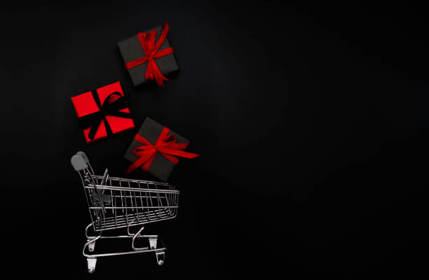 istock A small shopping cart is filled with gifts. Objects on a black background, black Friday concept. 1345539821