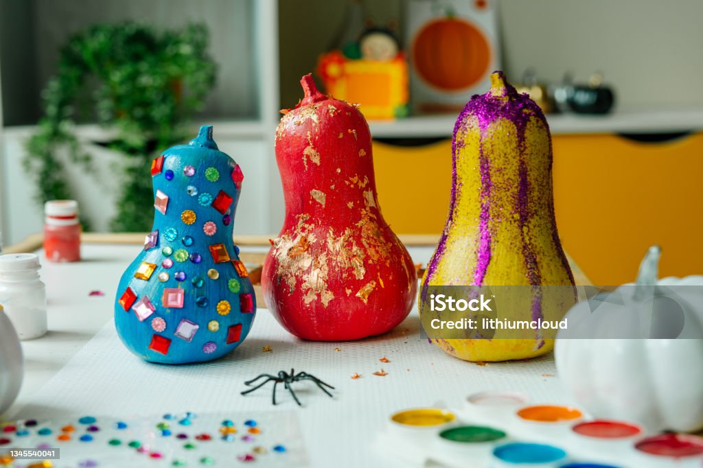 Decorating pumpkins with patal foil. Idea for Halloween DIY art class Decorated pumpkins with stickers, patal foil and glitter on the table. Idea for Halloween DIY art class for children. Selected focus. Paint Stock Photo