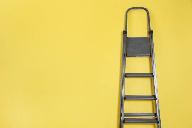 istock Metal stepladder on yellow background. Space for text 1345540385