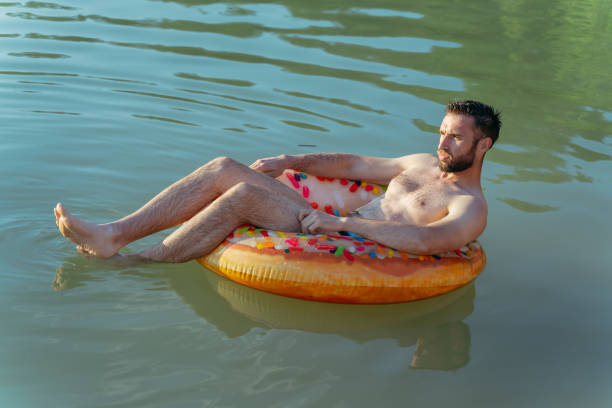 istock Rest. A man swims on an inflatable ring in a pond. 1345541307