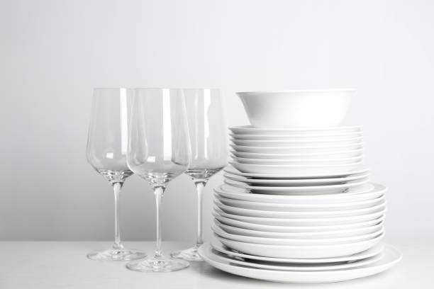 istock Stack of clean plates and glasses on white background 1345541400