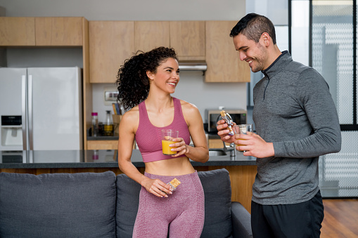 Happy couple at home eating a healthy post-workout snack and smiling - healthy eating concepts
