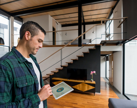 Latin American man controlling his house using a home automation system on a tablet - smart home concepts