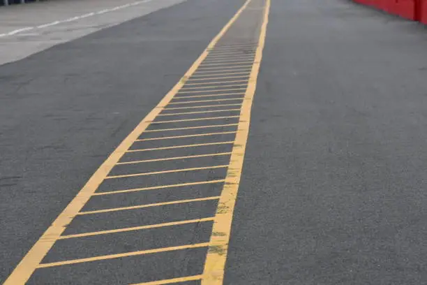 A yellow diagonal chevron strip restricting access along a tarmac straight in a pit-lane