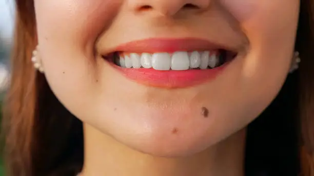 unrecognizable young woman with straight white teeth smiling at camera, close-up