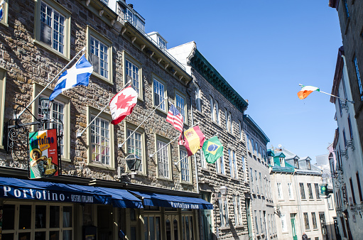 Six national flags above Portofino restaurant in Old Quebec during day of autumn