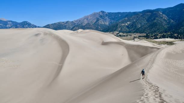 Hiker on the Great Sand Dunes Hiker on the Great Sand Dunes great sand dunes national park stock pictures, royalty-free photos & images