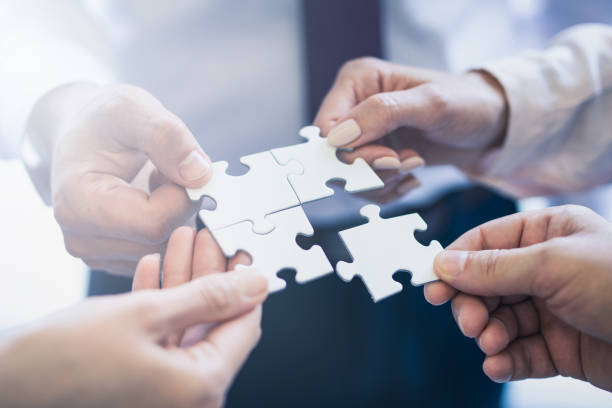 A group of business people assembling jigsaw puzzle. stock photo