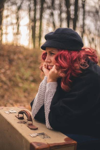 The girl walks along the path in the woods to the light in jacket and jeans.