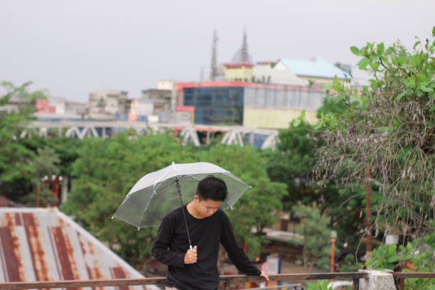young men standing with an umbrella in a city park - umbrella men business businessman imagens e fotografias de stock