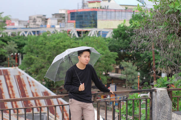 jóvenes de pie con un paraguas en un parque de la ciudad - umbrella men business businessman fotografías e imágenes de stock