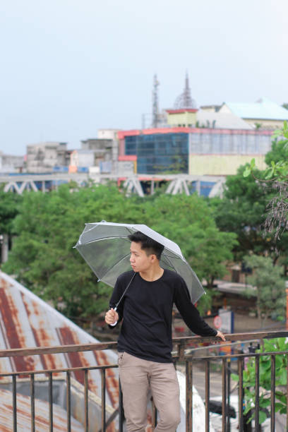 jóvenes de pie con un paraguas en un parque de la ciudad - umbrella men business businessman fotografías e imágenes de stock