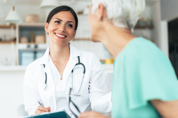 Healthcare worker at home visit Young smiling doctor is consulting a modern senior woman - patient, on the visit at home doctor consultation stock pictures, royalty-free photos & images