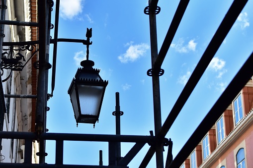 Street lamp among scaffolding on blue sky background