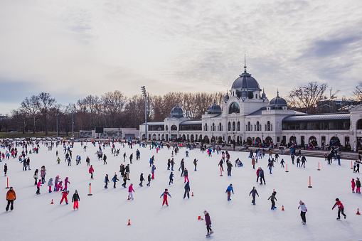 BUDAPEST, HUNGARY - DECEMBER 31, 2018: Many people spend their holidays skating in City Park ice rink in Budapest, Hungary. City Park is Europe's largest outdoor ice skating rink in the winter and a lake for boating in the summer