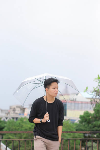 young men standing with an umbrella in a city park - umbrella men business businessman imagens e fotografias de stock