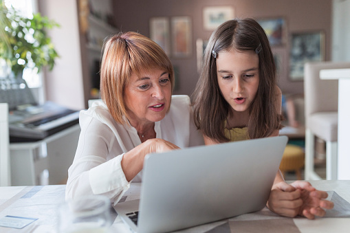 Mature woman and a young girl finishing online school homework together