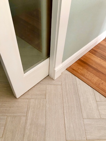 Low angle closeup of white pocket door and frame with parquet tile floor