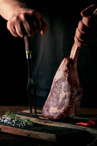 istock A man holds a Raw Tomahawk steak on a bone of dry aged beef on a dark background 1345557893