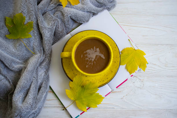 istock coffee cup, autumn leaves, book on wooden background 1345558453