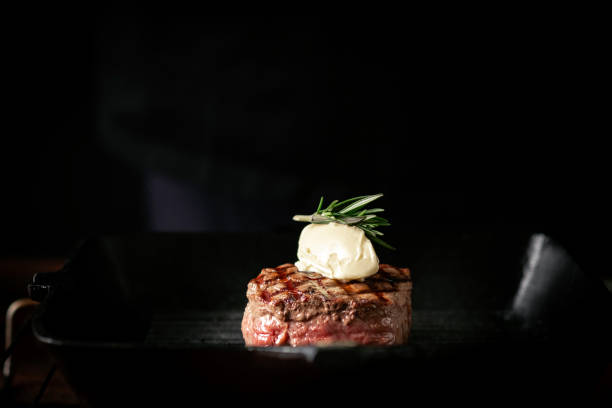 bistecca di filetto di manzo alla griglia in una padella con burro su uno sfondo scuro - filet mignon fillet steak dinner foto e immagini stock