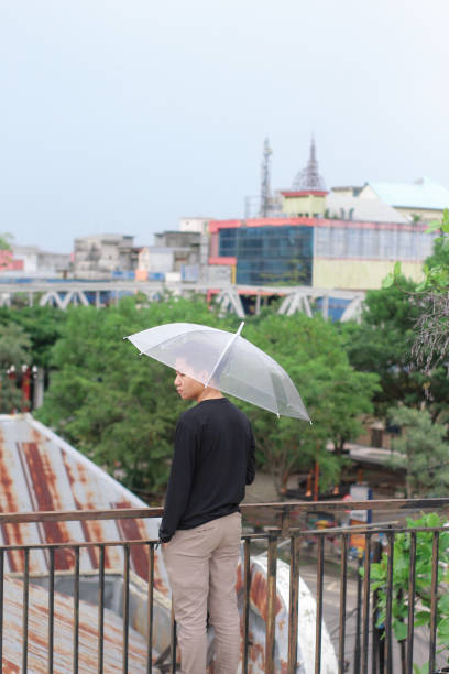 jóvenes solos con un paraguas en un parque de la ciudad - umbrella men business businessman fotografías e imágenes de stock