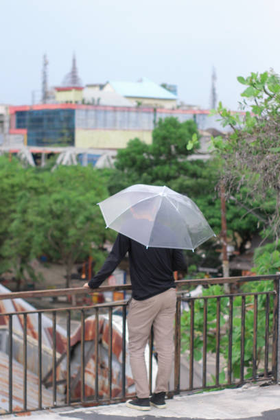 young men lonely with an umbrella in a city park - umbrella men business businessman imagens e fotografias de stock