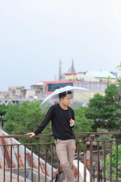 jóvenes solos con un paraguas en un parque de la ciudad - umbrella men business businessman fotografías e imágenes de stock