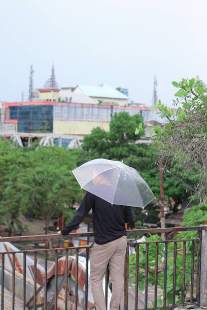 jóvenes solos con un paraguas en un parque de la ciudad - umbrella men business businessman fotografías e imágenes de stock