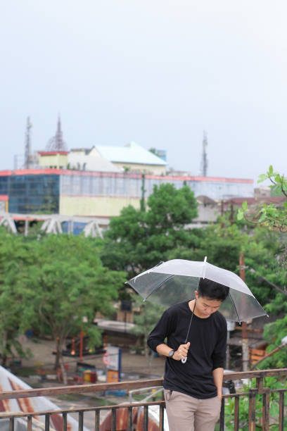young men lonely with an umbrella in a city park - umbrella men business businessman imagens e fotografias de stock