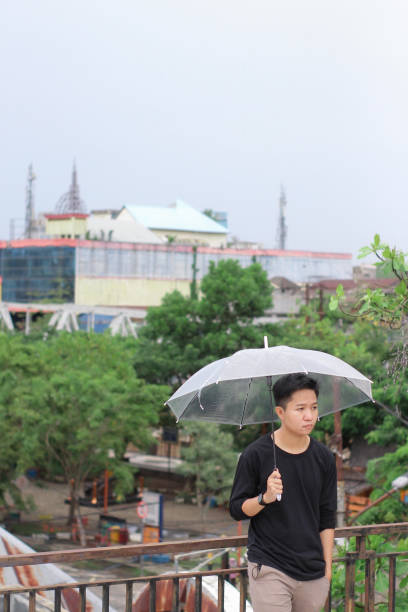 jóvenes solos con un paraguas en un parque de la ciudad - umbrella men business businessman fotografías e imágenes de stock