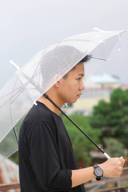 jóvenes con un paraguas en un parque de la ciudad - umbrella men business businessman fotografías e imágenes de stock