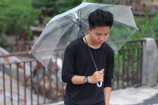 young men lonely with an umbrella in a city park - umbrella men business businessman imagens e fotografias de stock