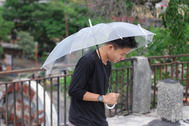 young men lonely with an umbrella in a city park - umbrella men business businessman imagens e fotografias de stock