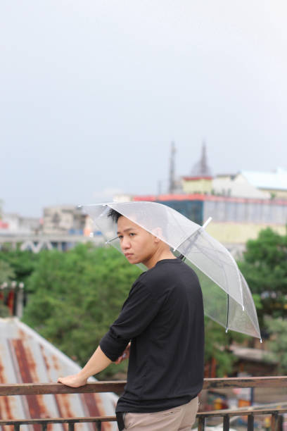 young men lonely with an umbrella in a city park - umbrella men business businessman imagens e fotografias de stock