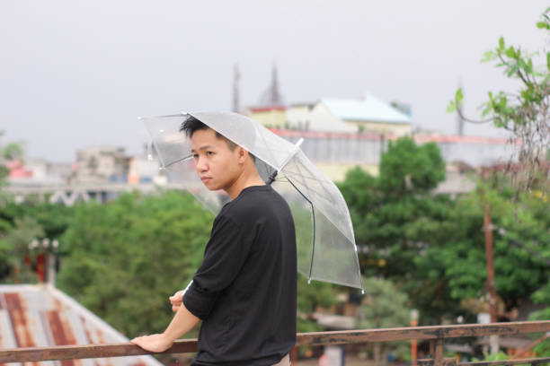 jóvenes solos con un paraguas en un parque de la ciudad - umbrella men business businessman fotografías e imágenes de stock