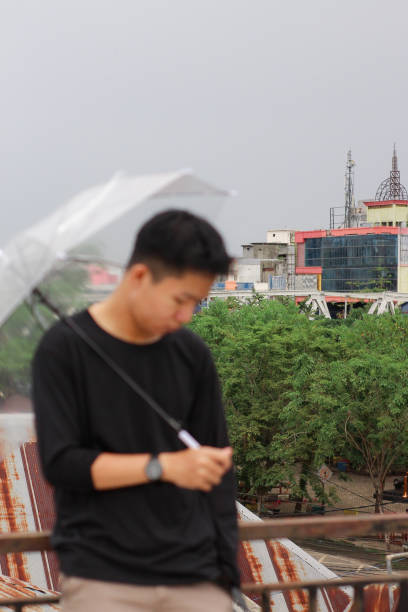 jóvenes solos con un paraguas en un parque de la ciudad - umbrella men business businessman fotografías e imágenes de stock