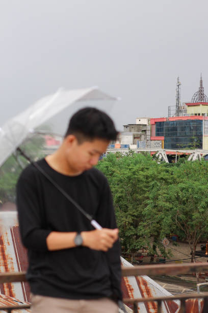 young men lonely with an umbrella in a city park - umbrella men business businessman imagens e fotografias de stock