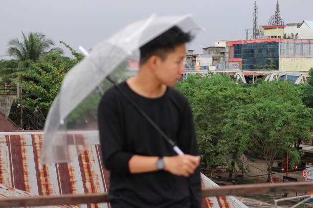 jóvenes solos con un paraguas en un parque de la ciudad - umbrella men business businessman fotografías e imágenes de stock