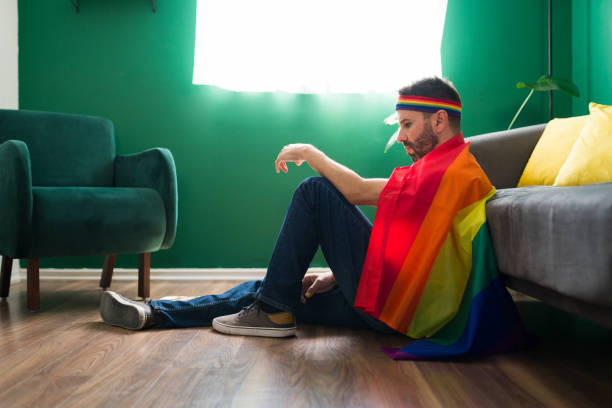 Latin man asking for equal gay rights Fighting for equality. Sad gay man wrapped a rainbow flag and ready to defend the LGBTQ community sad gay stock pictures, royalty-free photos & images
