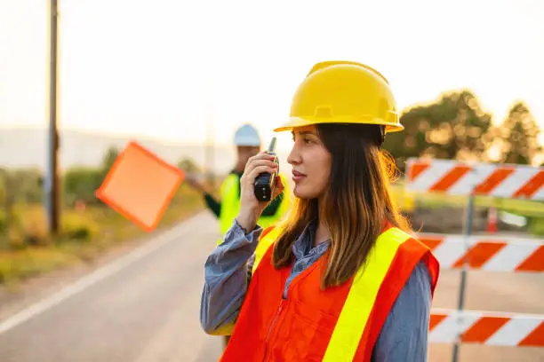 Photo of Communication in the Field Hispanic Workers Setting Barriers and Directing Traffic Street Road and Highway Construction Photo Series