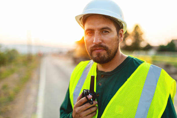 serious portrait of hispanic workers setting barriers and directing traffic street road and highway construction fotoserie - construction safety mid adult men road construction stock-fotos und bilder