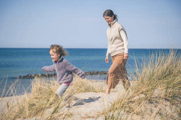 istock Mother and daughter outdoors on sandy beach 1345565072