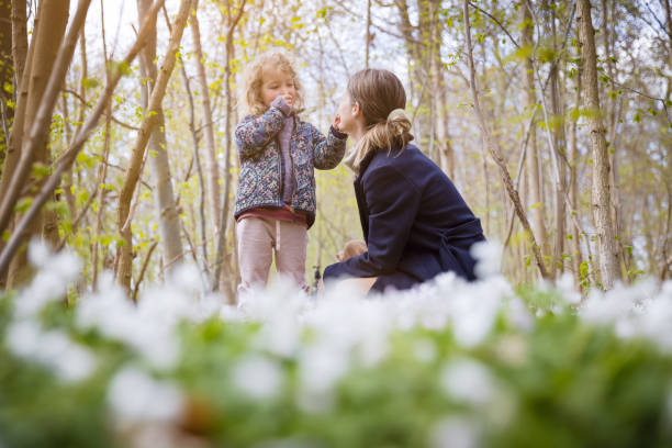 Child with bluebells. Little girl in pretty dress playing in beautiful spring forest with purple bluebell flowers. Kids hiking in park with blue bell flower meadow. Preschooler exploring nature.