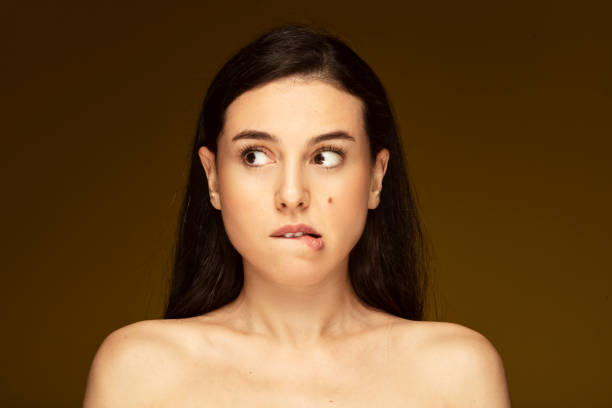 portrait of anxious woman with mole on her cheek, waiting anxiously. - biting lip imagens e fotografias de stock