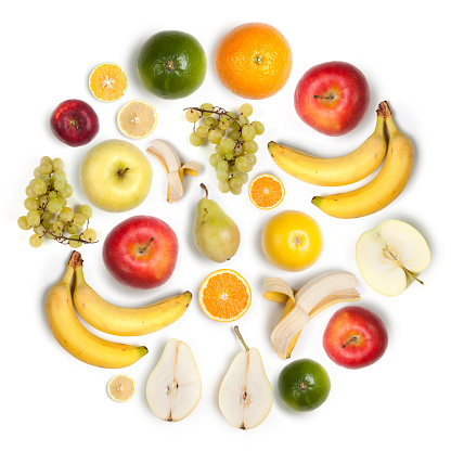 Composition made with many healthy fruits arranged together in a circular shape on white background: apples, bananas, lemons, oranges, pears and grapes.